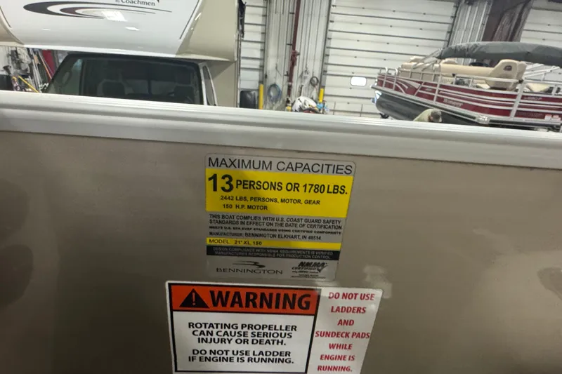 Slide: The Image of 2014 Bennington 22 SSX boat capacity label, warning signs, and interior view in a garage. - 9