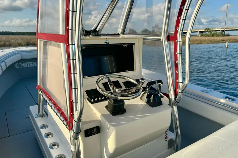Slide: The Image of 2006 Contender 33 Tournament boat helm with steering wheel and controls, on calm water. - 22