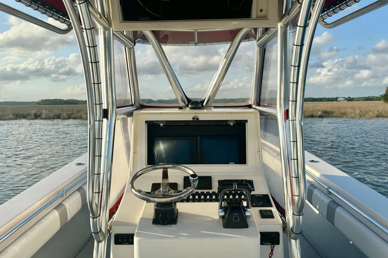 Slide: The Image of 2006 Contender 33 Tournament boat console with steering wheel and controls, on calm water. - 24
