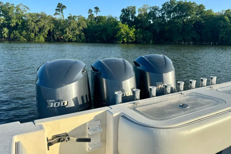 Slide: The Image of Triple Yamaha 300 engines on a 2006 Contender 33 Tournament boat by a scenic river. - 30