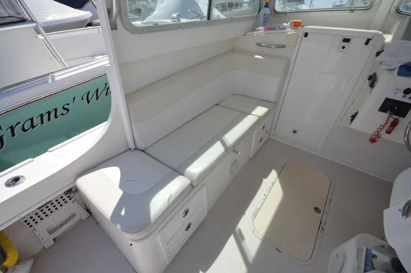 Slide: The Image of Interior of a 2009 Steiger Craft 26 Miami boat, featuring white seating and storage compartments. - 21