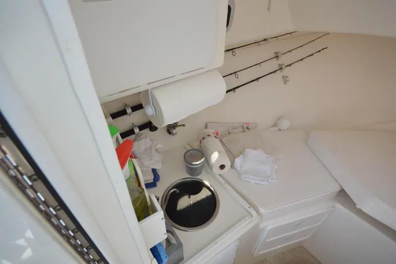 Slide: The Image of 2009 Steiger Craft 26 Miami cabin interior with fishing rods and kitchenette essentials. - 26