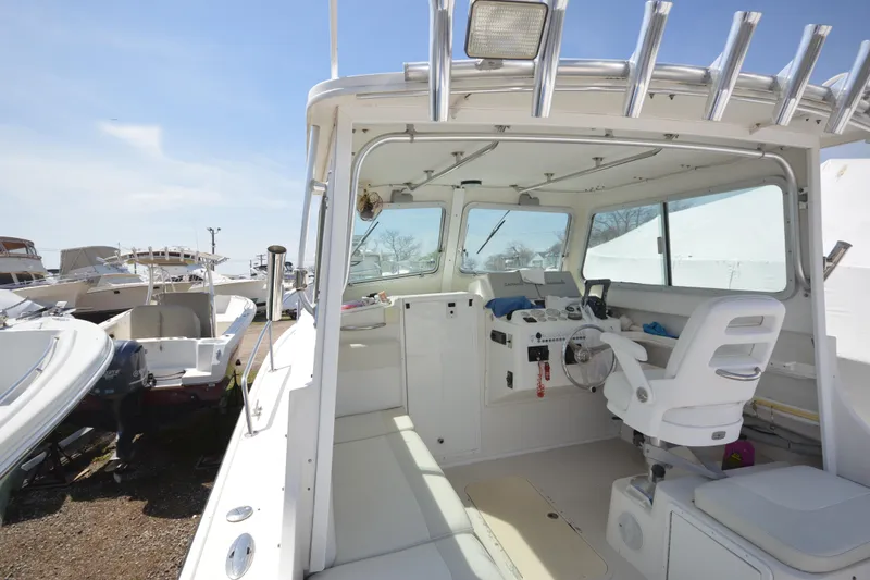 Slide: The Image of 2009 Steiger Craft 26 Miami boat interior with helm and seating, docked under clear skies. - 9