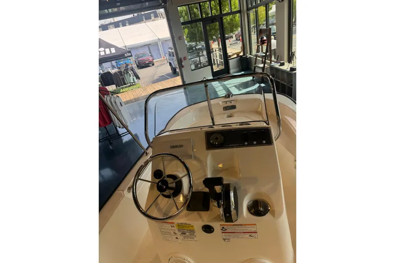 Slide: The Image of 2026 Boston Whaler 150 Montauk boat interior with steering wheel and controls in showroom. - 4