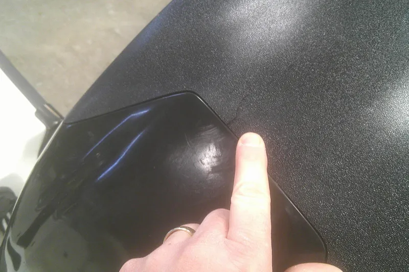 Slide: The Image of Close-up of a 2012 Boston Whaler 150 Montauk with a finger pointing at a surface crack. - 13