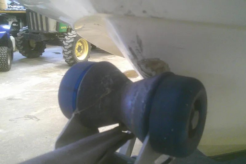 Slide: The Image of 2012 Boston Whaler 150 Montauk hull damage near trailer roller in garage. - 18