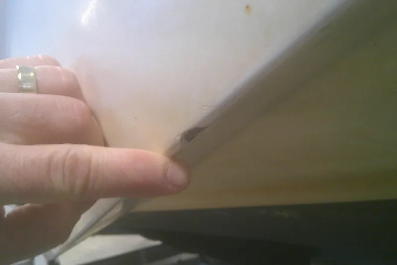 Slide: The Image of Close-up of a 2012 Boston Whaler 150 Montauk hull damage, with a hand pointing. - 20