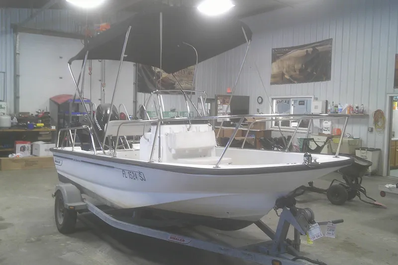 Slide: The Image of 2012 Boston Whaler 150 Montauk boat on trailer in a garage setting. - 3