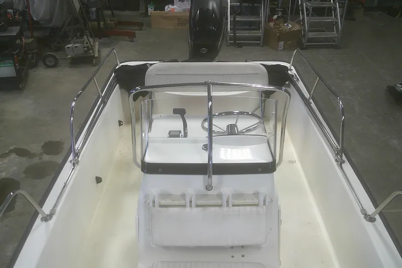 Slide: The Image of 2012 Boston Whaler 150 Montauk boat interior with steering console in a garage setting. - 8