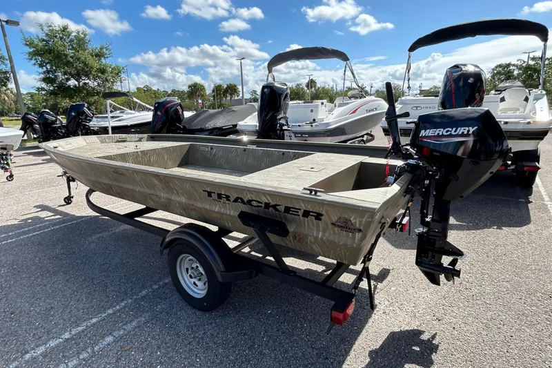 Slide: The Image of 2025 Tracker Grizzly 1754 Jon boat with Mercury engine on trailer, parked outdoors. - 2