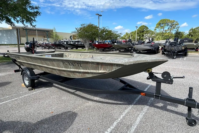 Slide: The Image of 2025 Tracker Grizzly 1754 Jon boat on trailer in parking lot under blue sky. - 4