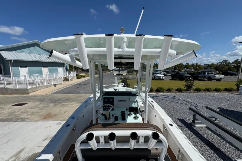 Slide: The Image of 2020 Crevalle 24 HCO boat with T-top and rod holders, parked outdoors under clear sky. - 10