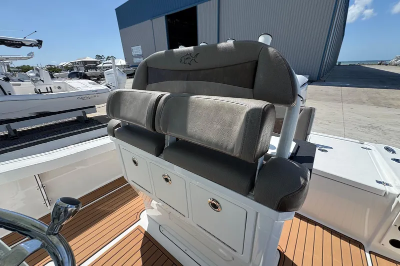 Slide: The Image of 2020 Crevalle 24 HCO boat with cushioned seating and storage, docked near a warehouse. - 14