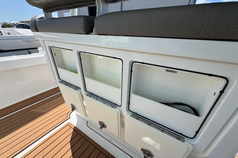 Slide: The Image of 2020 Crevalle 24 HCO boat storage compartments with cushioned seating and teak flooring. - 15