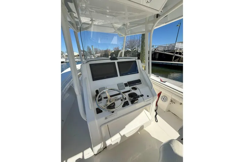 Slide: The Image of 2017 Regulator 31 boat helm with dual screens and steering wheel, docked by the water. - 15