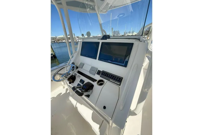 Slide: The Image of 2017 Regulator 31 boat dashboard with dual screens and steering wheel, docked at marina. - 27