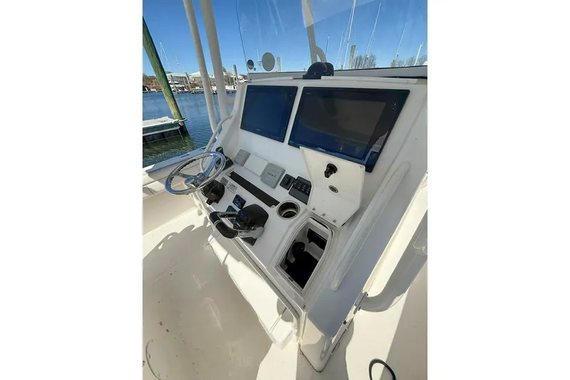 Slide: The Image of 2017 Regulator 31 boat helm with dual screens and steering wheel, docked at marina. - 28