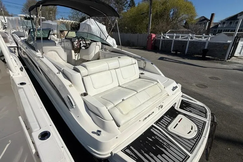 Slide: The Image of 2012 Sea Ray 260 Sundeck boat with white seating and black canopy, parked outdoors. - 5