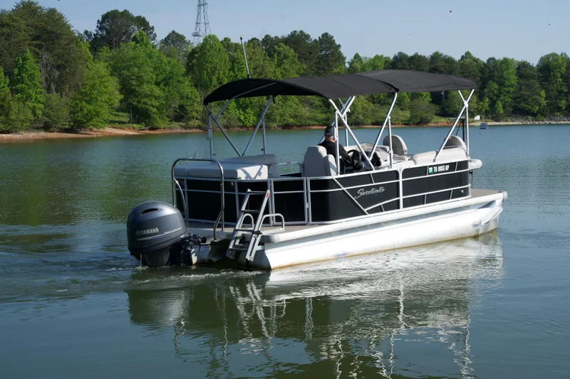 Slide: The Image of 2018 Godfrey Sweetwater20 pontoon boat cruising on a serene lake. - 13