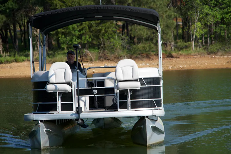 Slide: The Image of 2018 Godfrey Sweetwater20 pontoon boat cruising on a calm lake with lush greenery. - 18