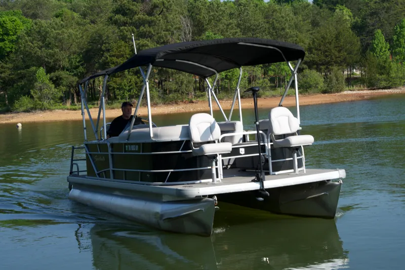 Slide: The Image of 2018 Godfrey Sweetwater20 pontoon boat cruising on a serene lake with lush green surroundings. - 19