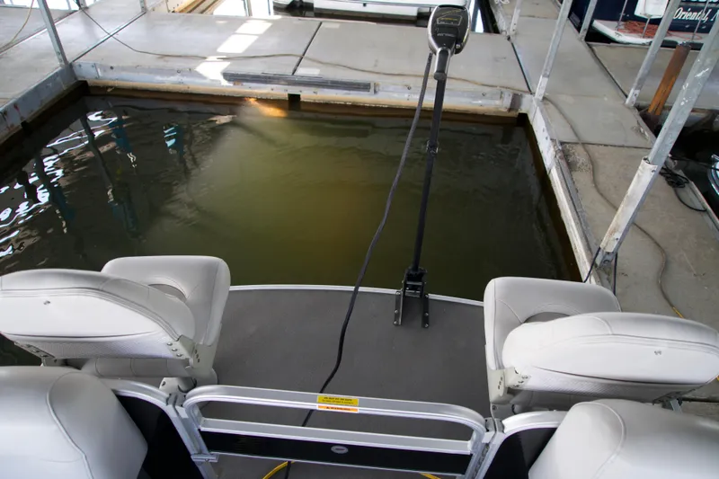 Slide: The Image of 2018 Godfrey Sweetwater 20 pontoon boat docked, featuring comfortable seating and a trolling motor. - 9