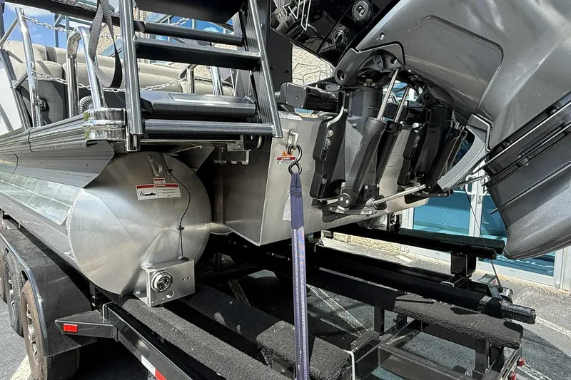 Slide: The Image of 2026 Barletta LUSSO 25UCAT pontoon boat on trailer, showcasing engine and ladder. - 43