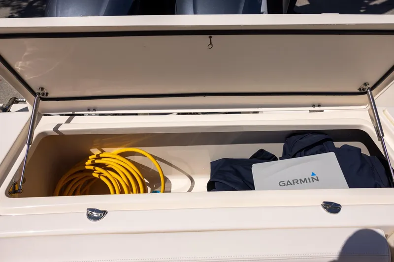Slide: The Image of Open storage compartment on 2016 Grady-White Canyon 306 boat with yellow hose and Garmin equipment. - 9