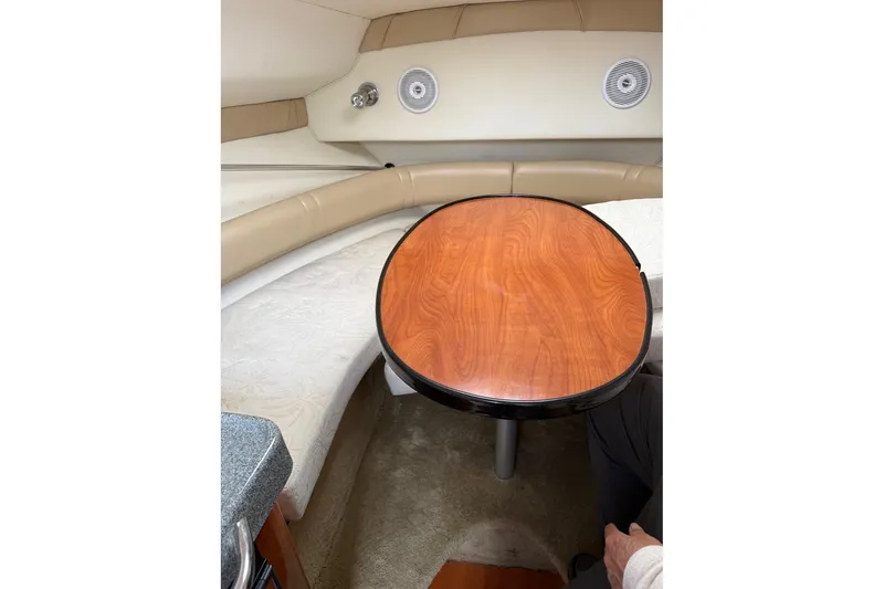 Slide: The Image of 2005 Larson Cabrio 240 interior with round wooden table and beige seating. - 12