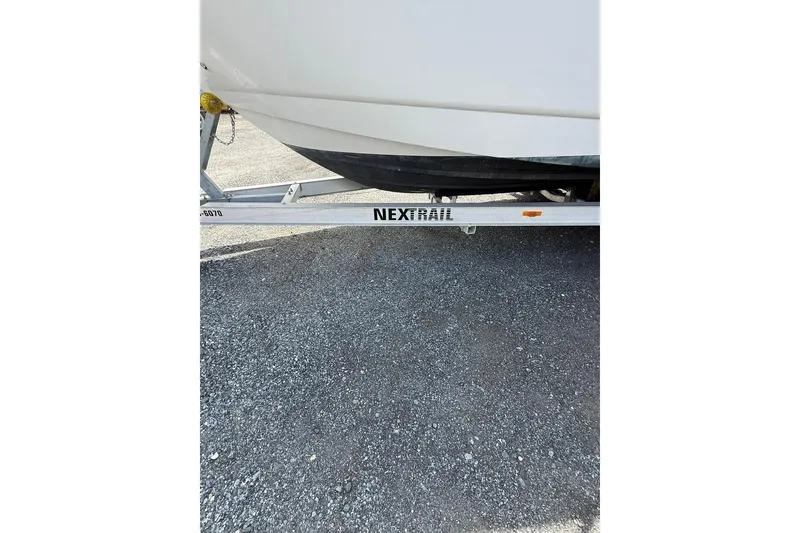 Slide: The Image of 2005 Larson Cabrio 240 boat on a NextRail trailer, parked on gravel. - 15