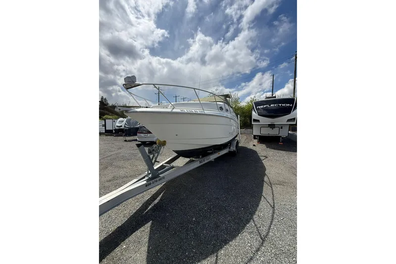 Slide: The Image of 2005 Larson Cabrio 240 boat on trailer under cloudy sky. - 2