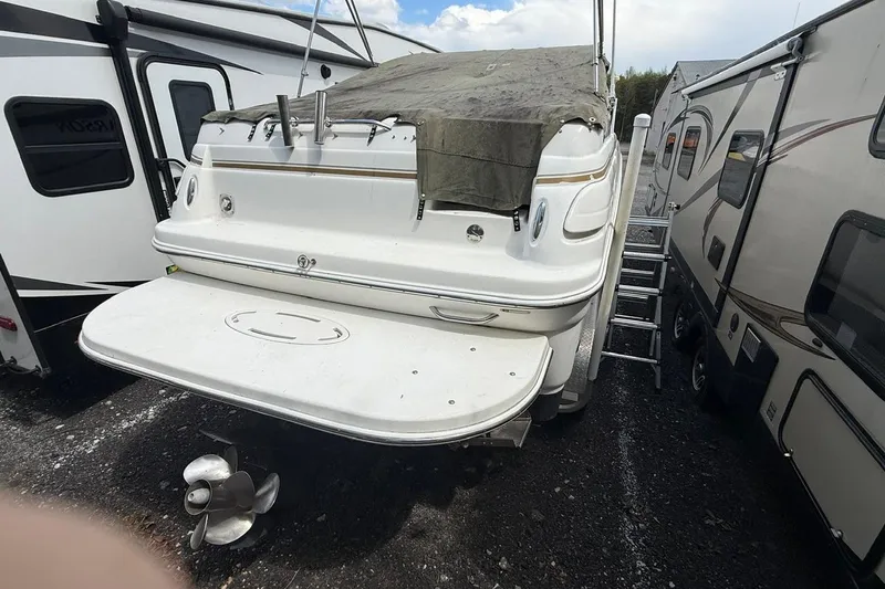 Slide: The Image of 2005 Larson Cabrio 240 boat with tarp cover, parked between RVs. - 3