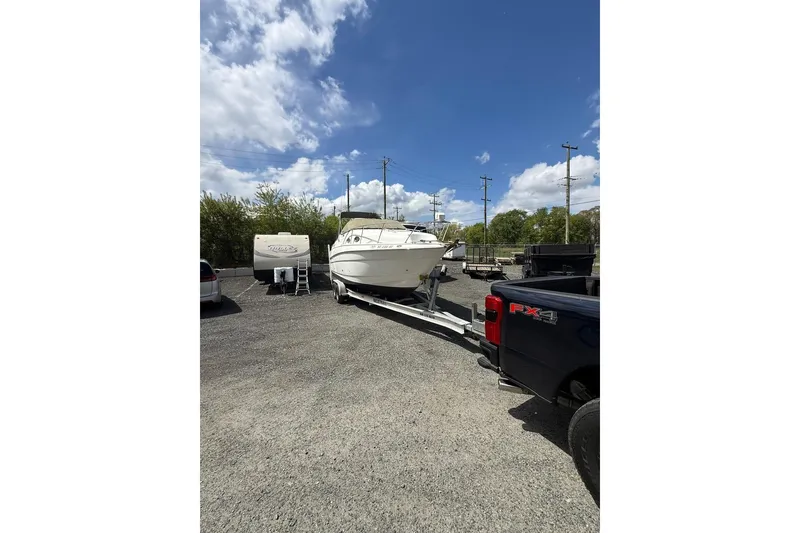 Slide: The Image of 2005 Larson Cabrio 240 boat on trailer in parking lot under blue sky. - 4