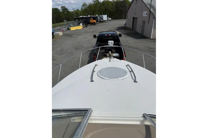 Slide: The Image of 2005 Larson Cabrio 240 boat on trailer, parked in a lot with vehicles. - 5