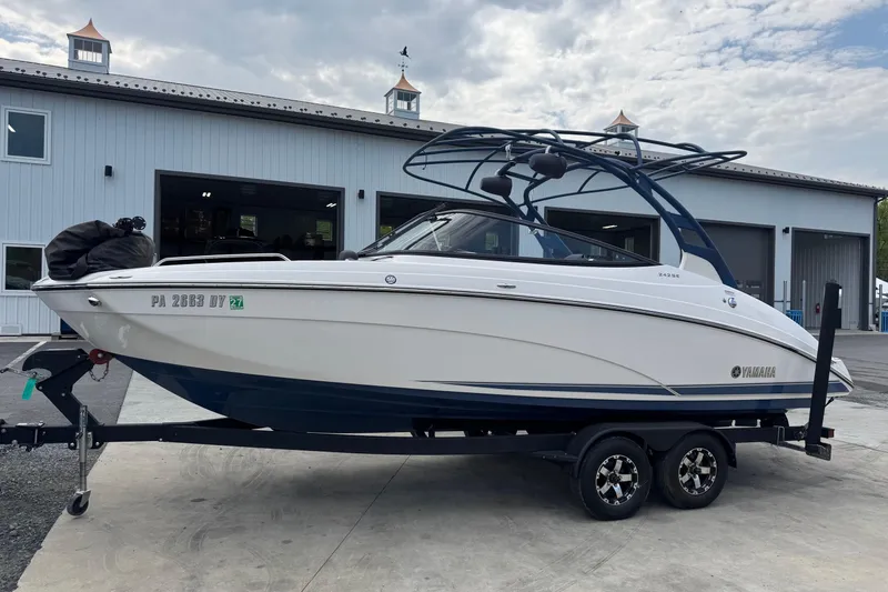 Slide: The Image of 2020 Yamaha Boats 242SE on trailer, parked outside a garage under a cloudy sky. - 3