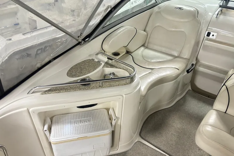 Slide: The Image of Interior of a 2008 Monterey 250 Cruiser boat with beige seating and a built-in cooler. - 10