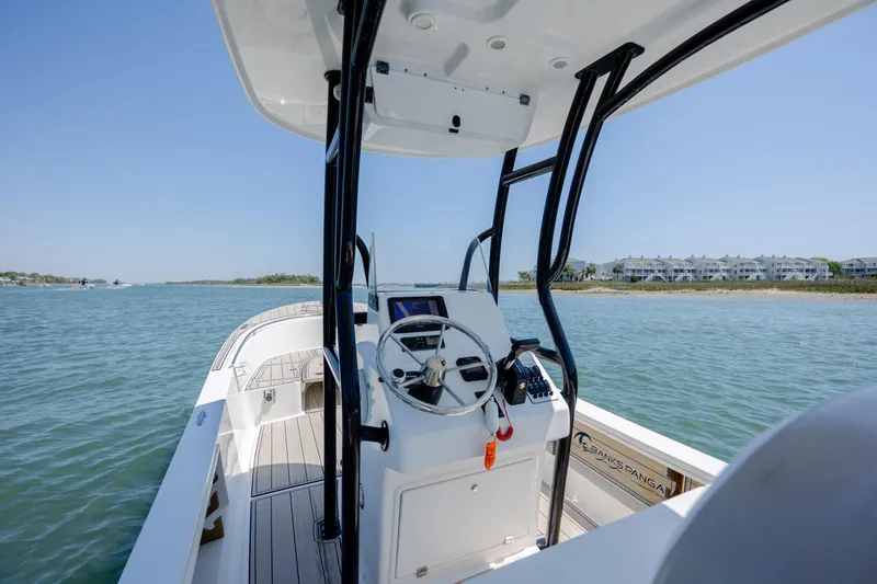 Slide: The Image of 2022 Banks Panga 26 boat on water, showcasing steering console and coastal view. - 13