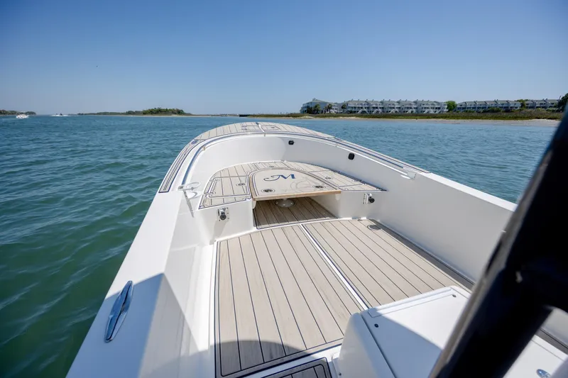 Slide: The Image of 2022 Banks Panga 26 boat on calm water, featuring sleek deck design and coastal backdrop. - 19