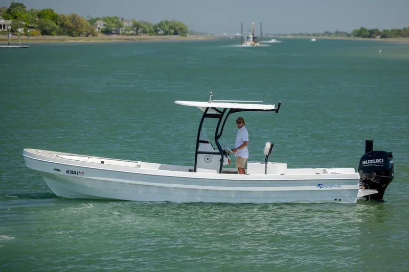 Slide: The Image of 2022 Banks Panga 26 boat cruising on a calm waterway with a Suzuki outboard motor. - 5