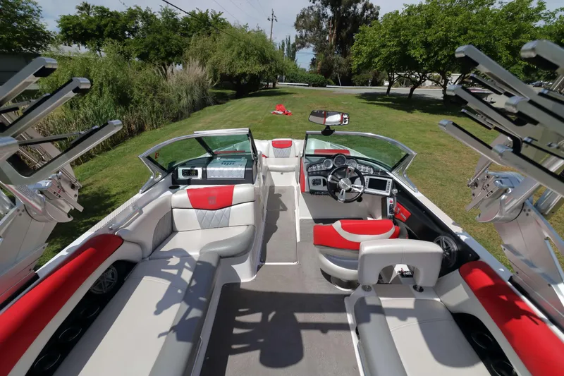 Slide: The Image of Interior of 2014 MasterCraft X-25 boat with red and white seating, parked on grass. - 13