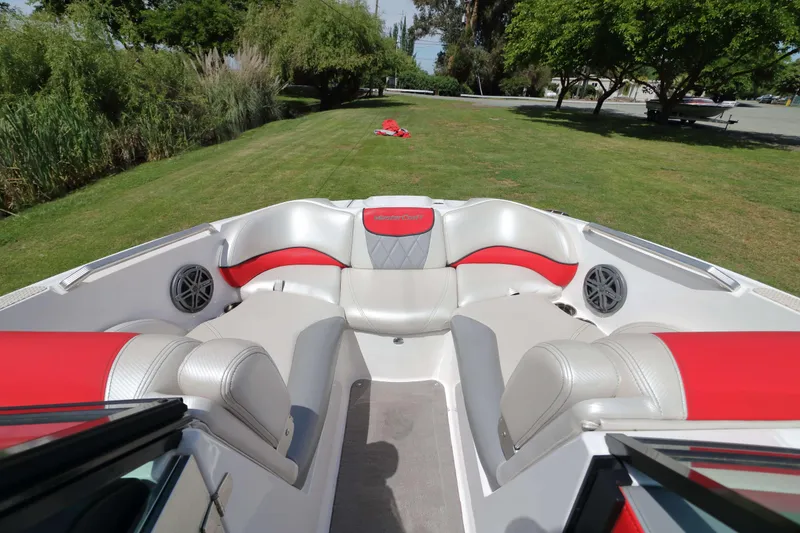 Slide: The Image of 2014 MasterCraft X-25 boat interior with red and gray seating on grassy area. - 14