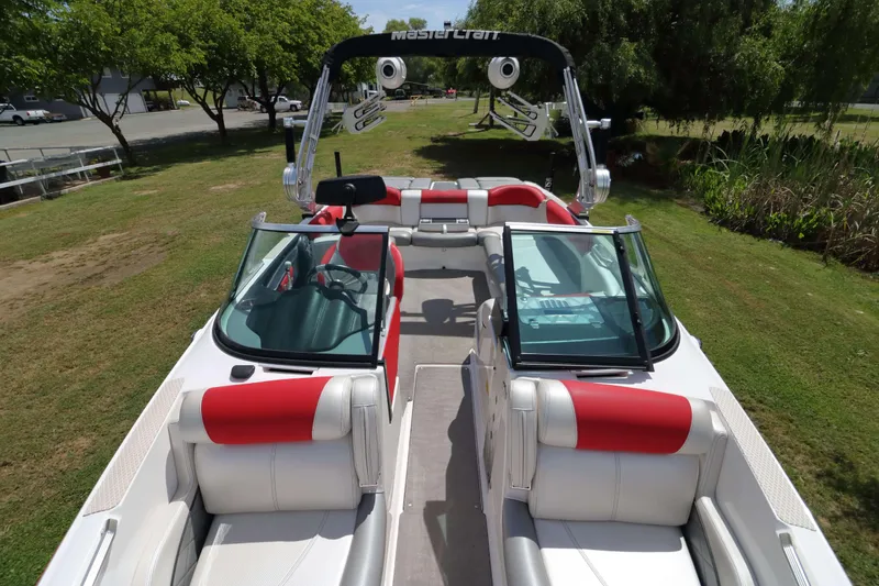 Slide: The Image of 2014 MasterCraft X-25 boat with red and white seating, parked on grass. - 16