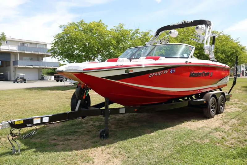 Slide: The Image of 2014 MasterCraft X-25 boat on trailer, vibrant red, parked on grass. - 7