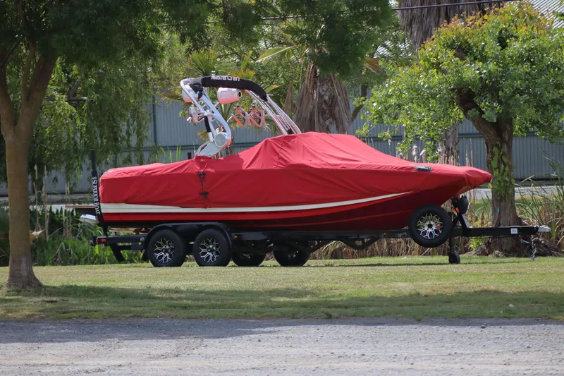 Slide: The Image of 2014 MasterCraft X-25 boat with red cover on trailer, parked on grass. - 9