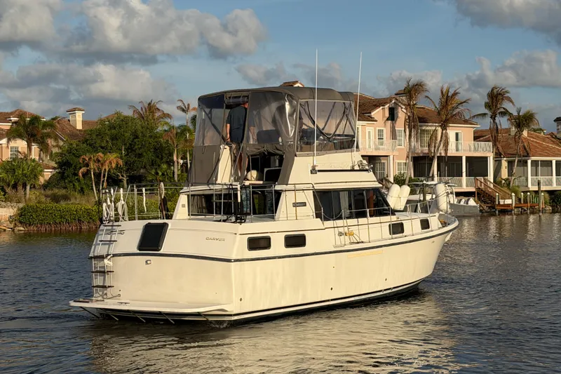 Slide: The Image of 1984 Carver 3607 Aft Cabin Motor Yacht cruising near waterfront homes. - 2