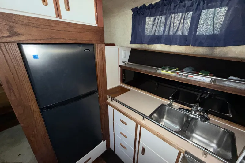 Slide: The Image of 1984 Carver 3607 Aft Cabin Motor Yacht kitchen with fridge, sink, and storage cabinets. - 24