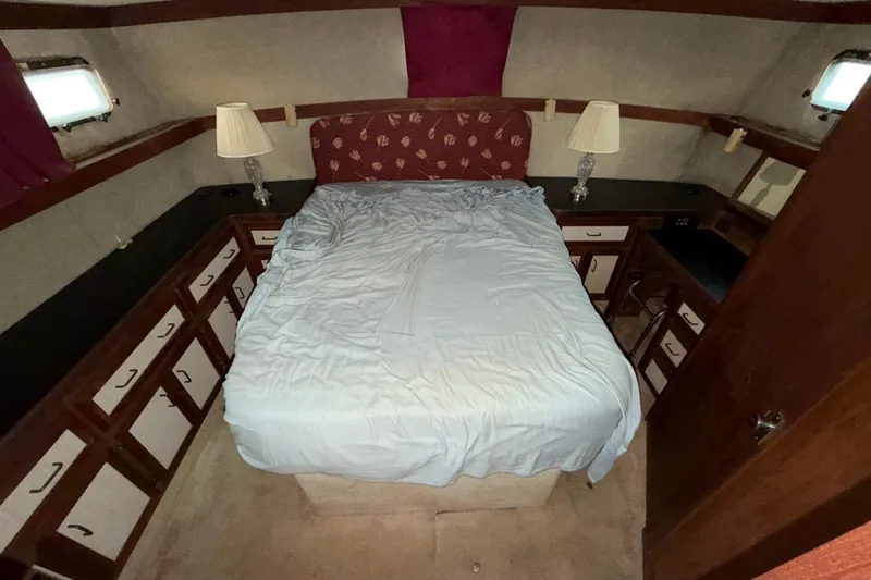 Slide: The Image of 1984 Carver 3607 Aft Cabin Motor Yacht bedroom with bed, lamps, and storage cabinets. - 32
