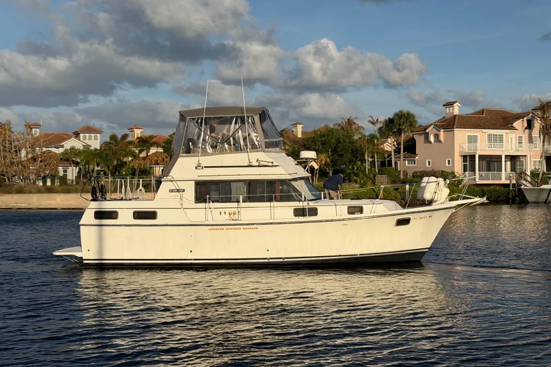 Slide: The Image of 1984 Carver 3607 Aft Cabin Motor Yacht cruising on a sunny day near waterfront homes. - 4