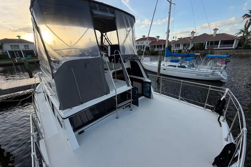 Slide: The Image of 1984 Carver 3607 Aft Cabin Motor Yacht docked at sunset, with sailboat nearby. - 5