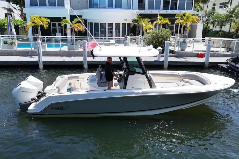The Image of 2024 Boston Whaler 280 Outrage boat docked near waterfront property with palm trees. - 0
